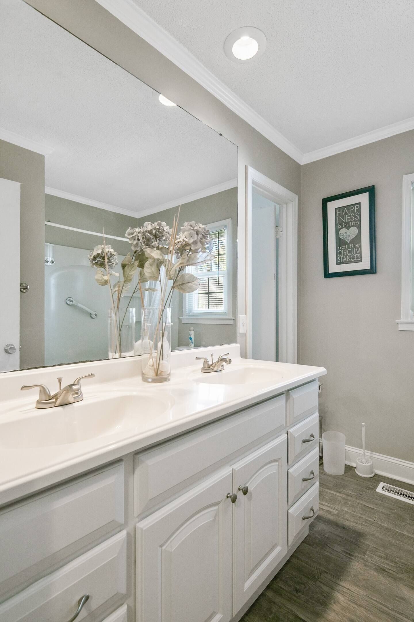 A bathroom with a double vanity, a large mirror, and a framed quote on the wall.