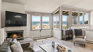 Ein Wohnzimmer mit Kamin, Fernseher und Blick auf den Strand.