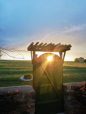 A wooden gate with a sun shining through it, surrounded by a wire fence and stone walls. - Cozy 1 Bed Cottage in Ognen, Near Karnobat, Burgas (Karnobat)