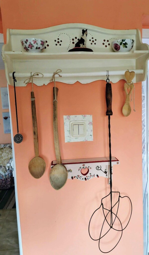 Una cocina con encimera blanca, un colgador para ollas y una estantería decorativa en la parte superior.