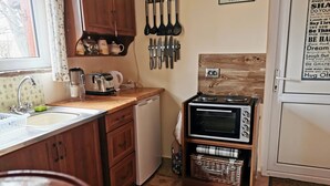 Une cuisine compacte avec des meubles de rangement en bois, un évier, un grille-pain, un four à micro-ondes et un petit réfrigérateur.