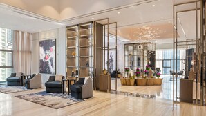 A spacious lobby with modern furniture, a large abstract painting, and a view of the city. - Paramount Hotel Midtown (Dubai)