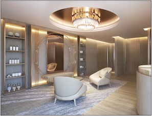 A modern, well-lit room with a chandelier, built-in shelving with toiletries, a seating area, and a vanity with a mirror.