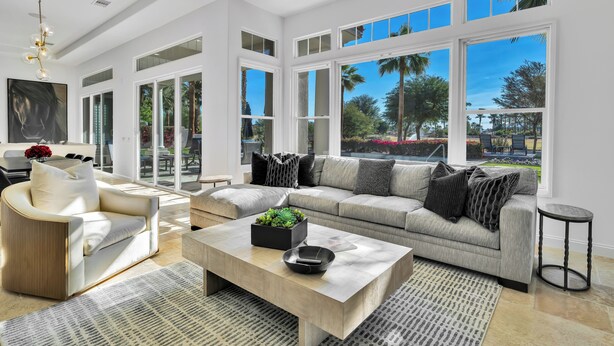 A spacious living room with a large window, a sofa, a coffee table, and a chair.