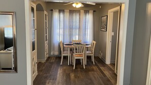 A dining area with a table and chairs, a ceiling fan, and a window with curtains. - Historic Mc Kennan Park Apt 2 (1 bed 1 bath) - KP220APT2 (Sioux Falls)