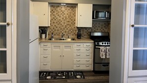 A compact kitchen with white cabinets, a microwave, a stove, and a sink. - Historic Mc Kennan Park Apt 2 (1 bed 1 bath) - KP220APT2 (Sioux Falls)