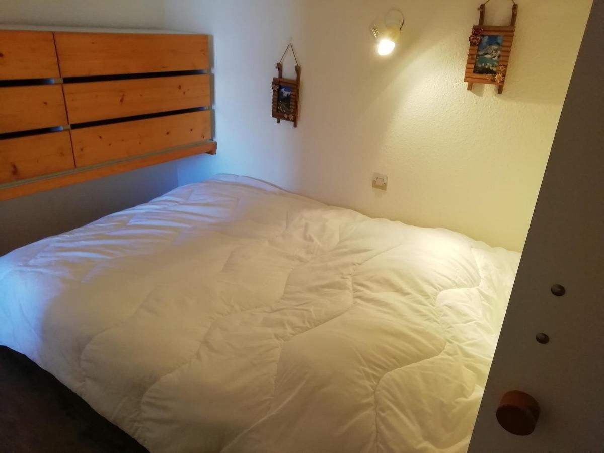 Ett sovrum med en säng, en sänggavel i trä, dekorationer på väggen och en lampa.