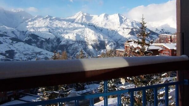 A mountain view with snow-covered peaks and a building with a red roof in the foreground.