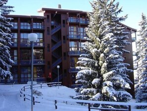 A multi-story building with a central staircase, surrounded by snow-covered trees. - 200m from resort center, 2nd floor, view valley, balcony, tv, 30m², Les Arcs (Les Arcs)