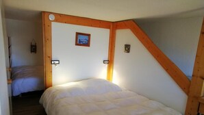 A bedroom with a single bed, wooden beams, and a small picture on the wall.