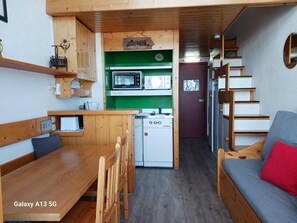 A compact kitchen with a microwave, a small refrigerator, and a sink. There is a wooden bench and a sofa with a red cushion. A staircase leads to an upper level. - 200m from resort center, 2nd floor, view valley, balcony, tv, 30m², Les Arcs (Les Arcs)