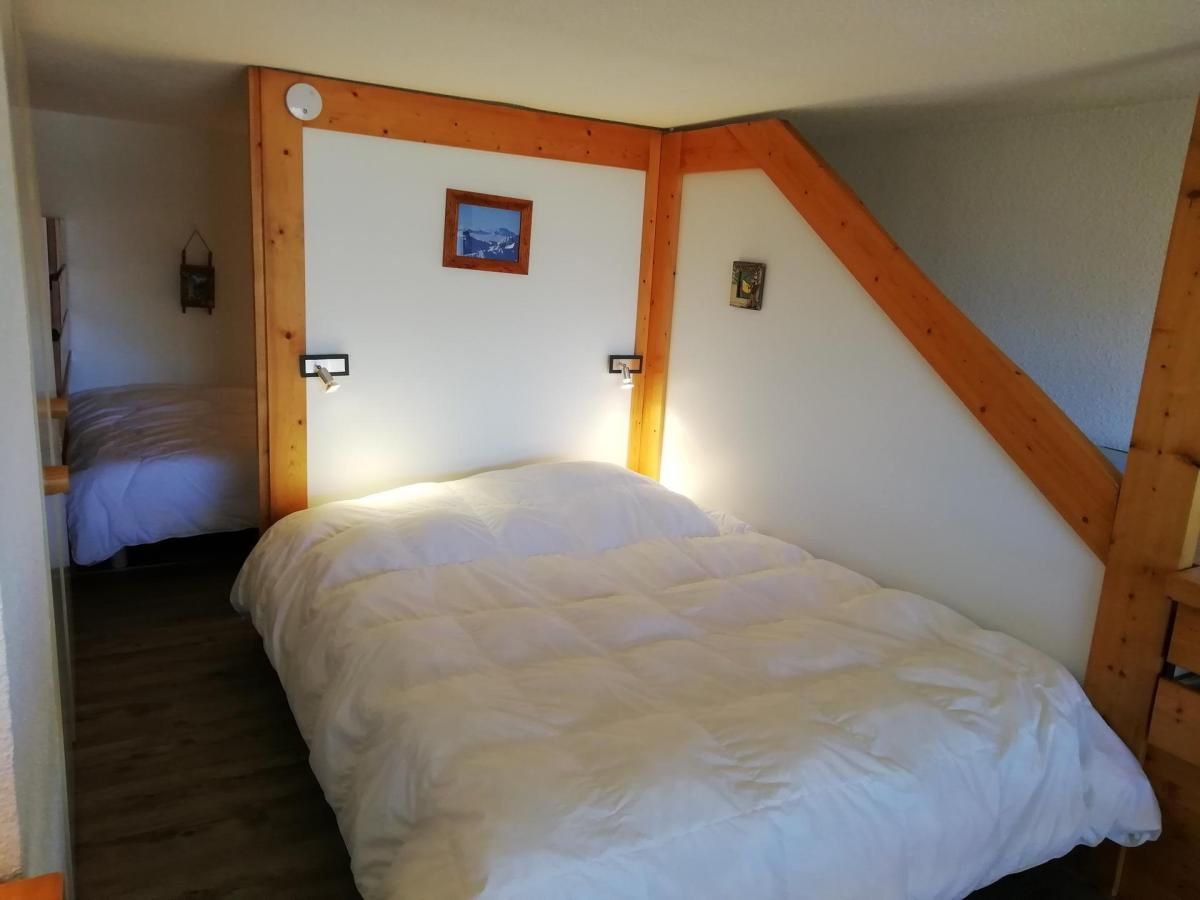 Ein Schlafzimmer mit einem Bett, Holzbalken, einem kleinen Bild an der Wand und einem Nachttisch.