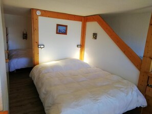 A bedroom with a bed, wooden beams, a small picture on the wall, and a nightstand. - 50m from ski slopes, 2nd floor, view valley, balcony, tv, 30m², Les Arcs (Les Arcs)