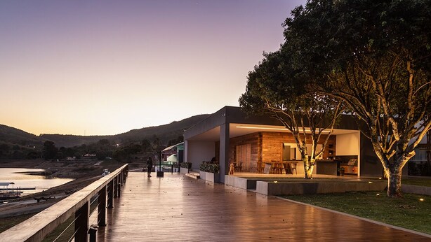 Un edificio moderno con terraza de madera, asientos exteriores y vista al agua.