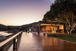 Un edificio moderno con terraza de madera, asientos exteriores y vista al agua.