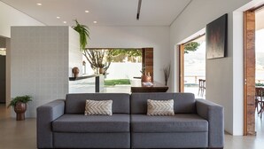Una sala de estar moderna con un sofá gris, una mesita de centro y un ventanal con vistas al exterior.