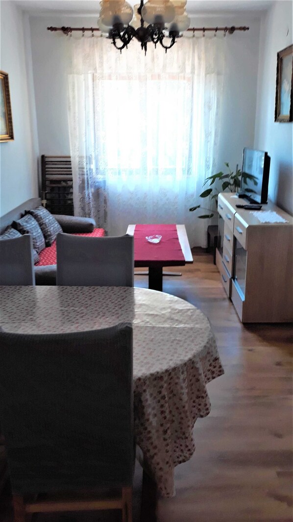 A cozy living room with a dining table, sofa, and a TV on a cabinet.