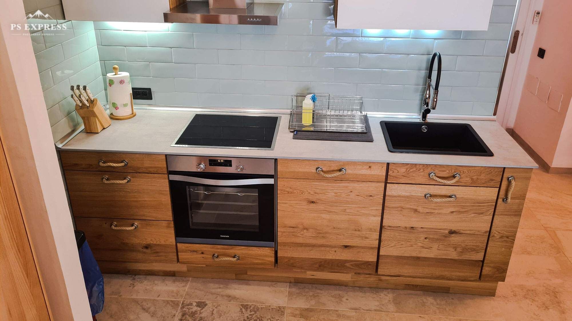 A modern kitchen with a built-in oven, a double sink, and wooden cabinetry.
