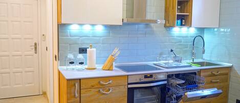 A kitchen with wooden cabinets, a built-in oven, a dishwasher, and a stainless steel sink.