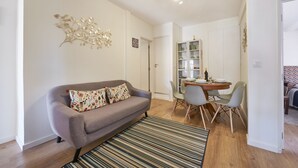 Ein modernes Wohnzimmer mit einem grauen Sofa, einem Esstisch mit Stühlen und einer Wanddekoration.