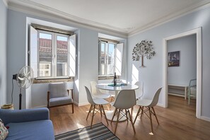 Uma sala de estar moderna com área de jantar, janelas amplas e um ventilador.