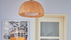 A door with frosted glass panels and a metal handle, a wicker pendant light above it, and a black and white photograph of a tram on the wall.