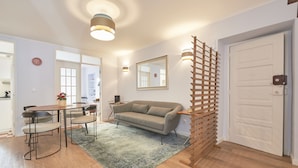 Un salon comprenant un canapé, une table à manger, des chaises, une cloison en bois et une porte.