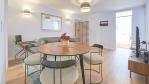 Un espace repas moderne avec une table ronde en bois, quatre chaises rembourrées et une plante en pot.