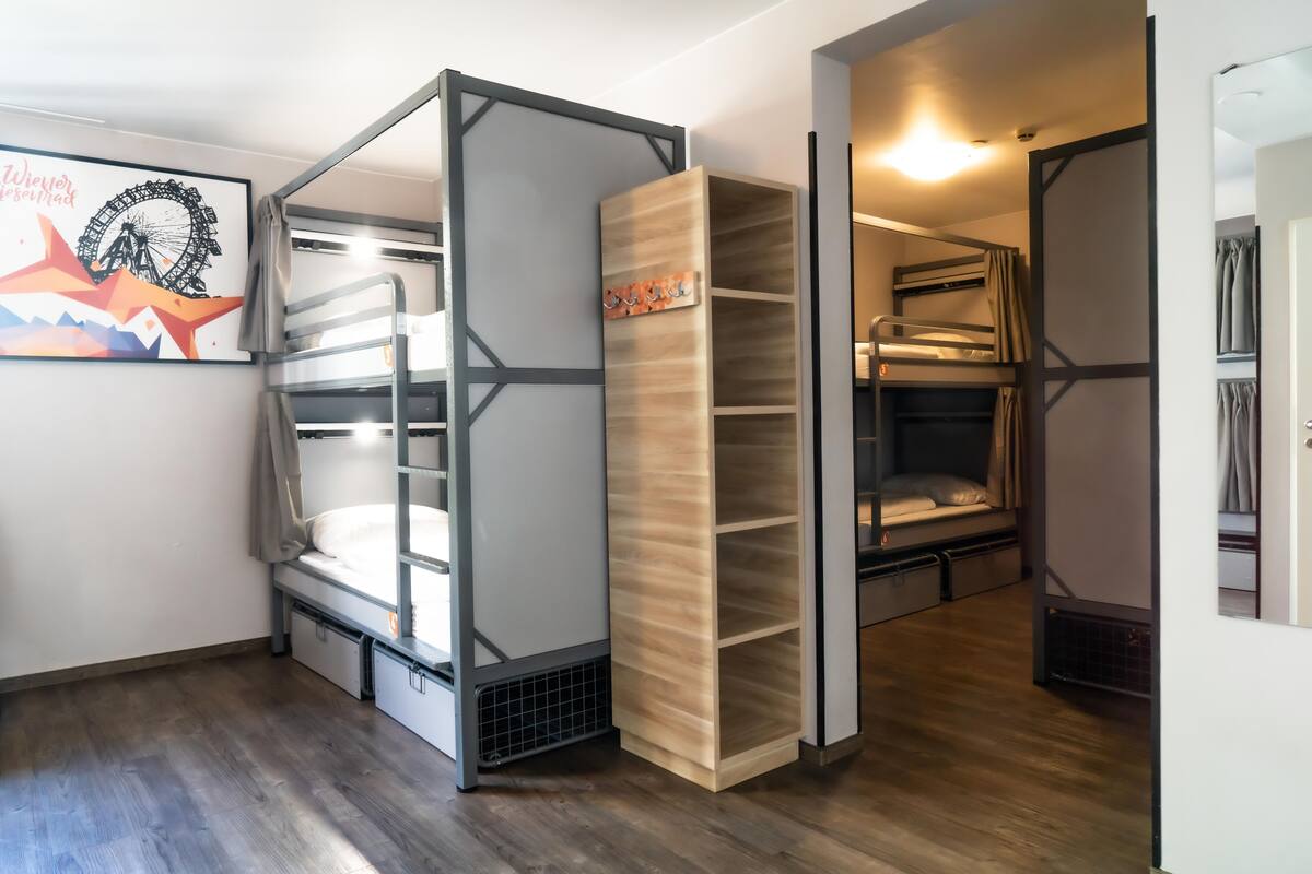 A compact room with bunk beds, a wooden shelf unit, and a framed picture on the wall.