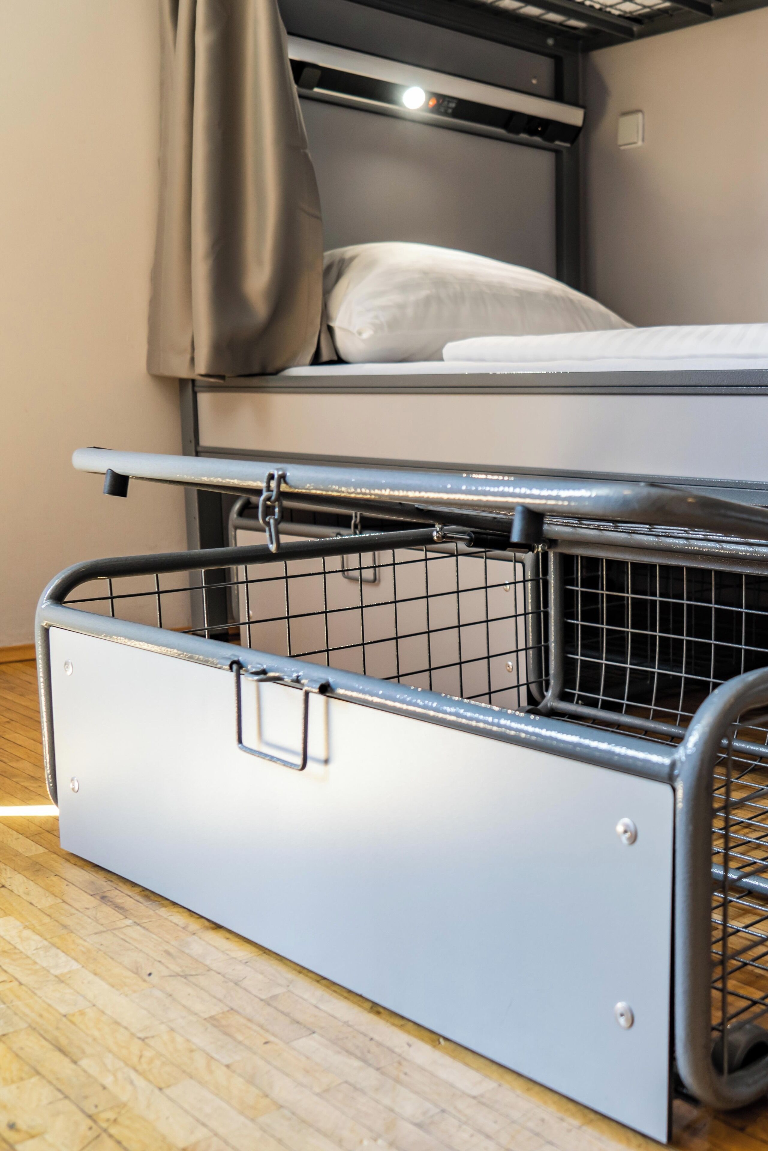 A bunk bed with a pull-out storage unit beneath it.