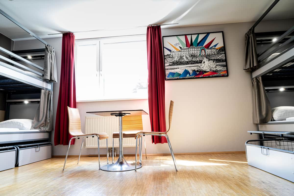 A dormitory room with bunk beds, a dining table, and a chair.