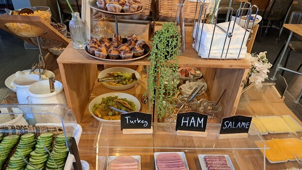 A buffet with labeled sections for Turkey, Ham, and Salame, along with various side dishes and utensils. - St Christopher's Vienna - Hostel (Vienna)