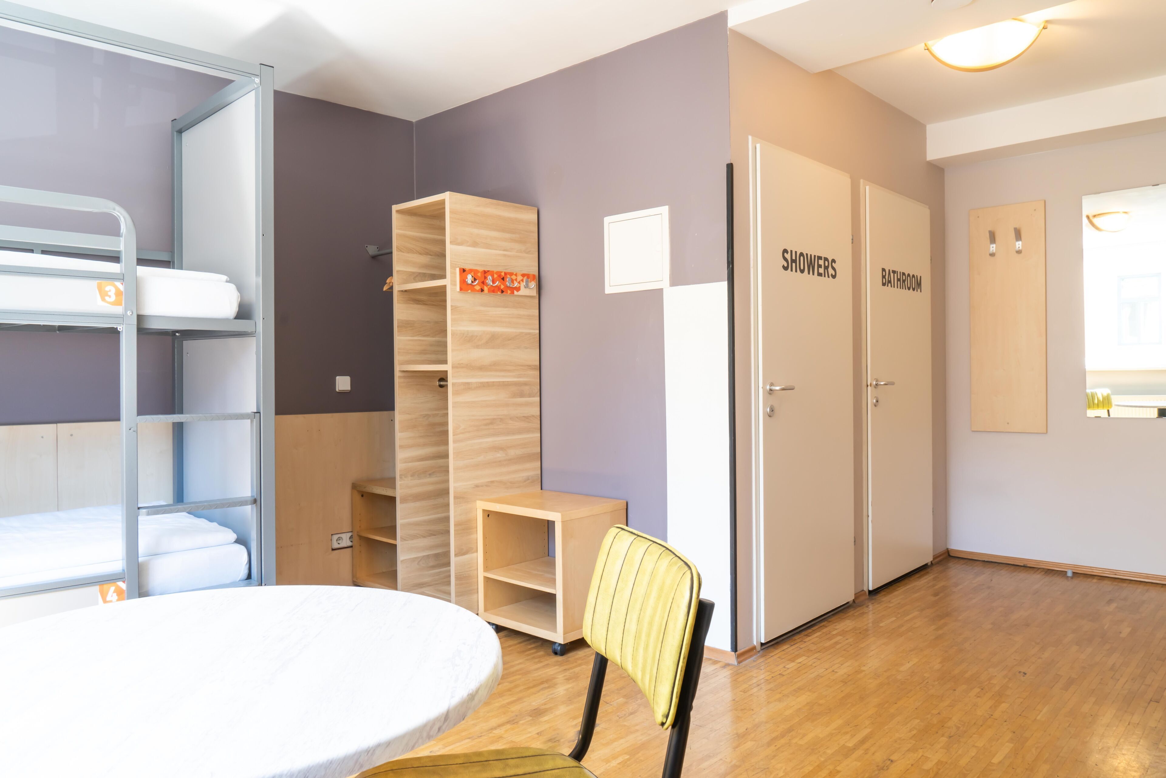 A room with bunk beds, a desk, a chair, and two doors labeled "showers" and "bathroom".