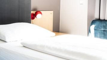 Una habitación de hotel con una cama, un cabecero de madera, una lámpara roja y una silla azul.