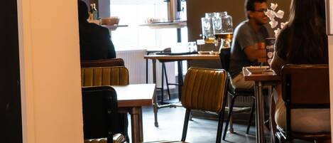 Ein Restaurantinneres mit Tischen, Stühlen, einem Fernseher und hängenden Lampen.