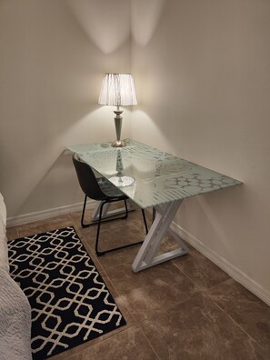 A small, well-lit room with a glass-top table, a black chair, a patterned rug, and a lamp. - Gulf Gate - Quaint and fresh 1st floor condo w/covered parking (Sarasota)