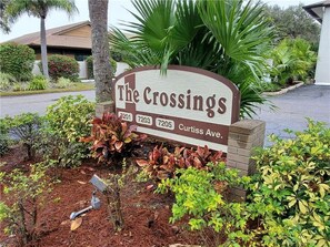 A sign for 'The Crossings' with three phone numbers and the address 'Curtiss Ave.' - Gulf Gate - Quaint and fresh 1st floor condo w/covered parking (Sarasota)