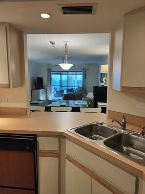 A modern kitchen with a built-in dishwasher, a double sink, and a dining area with a table and chairs.