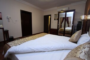 Una habitación de hotel con una cama grande, un escritorio y un armario.