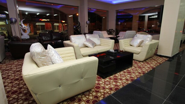 A spacious lobby with cream-colored sofas, a black coffee table, and a patterned carpet.