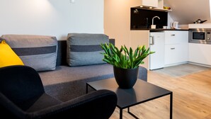 A modern living room with a grey sofa, a black armchair, and a black coffee table. There is a potted plant on the coffee table.
