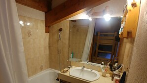 A bathroom with a bathtub, a sink, and a mirror. - Apartment in the Megeve valley (Praz-sur-Arly)
