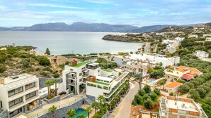 Un quartier résidentiel en bord de mer, avec des immeubles modernes, une vue dégagée sur la mer et un paysage montagneux en arrière-plan.