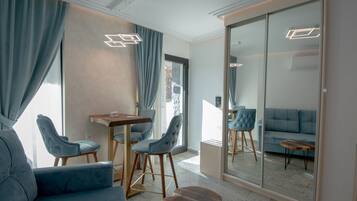 A modern living room with a sofa, two chairs, a small table, and a large mirror.