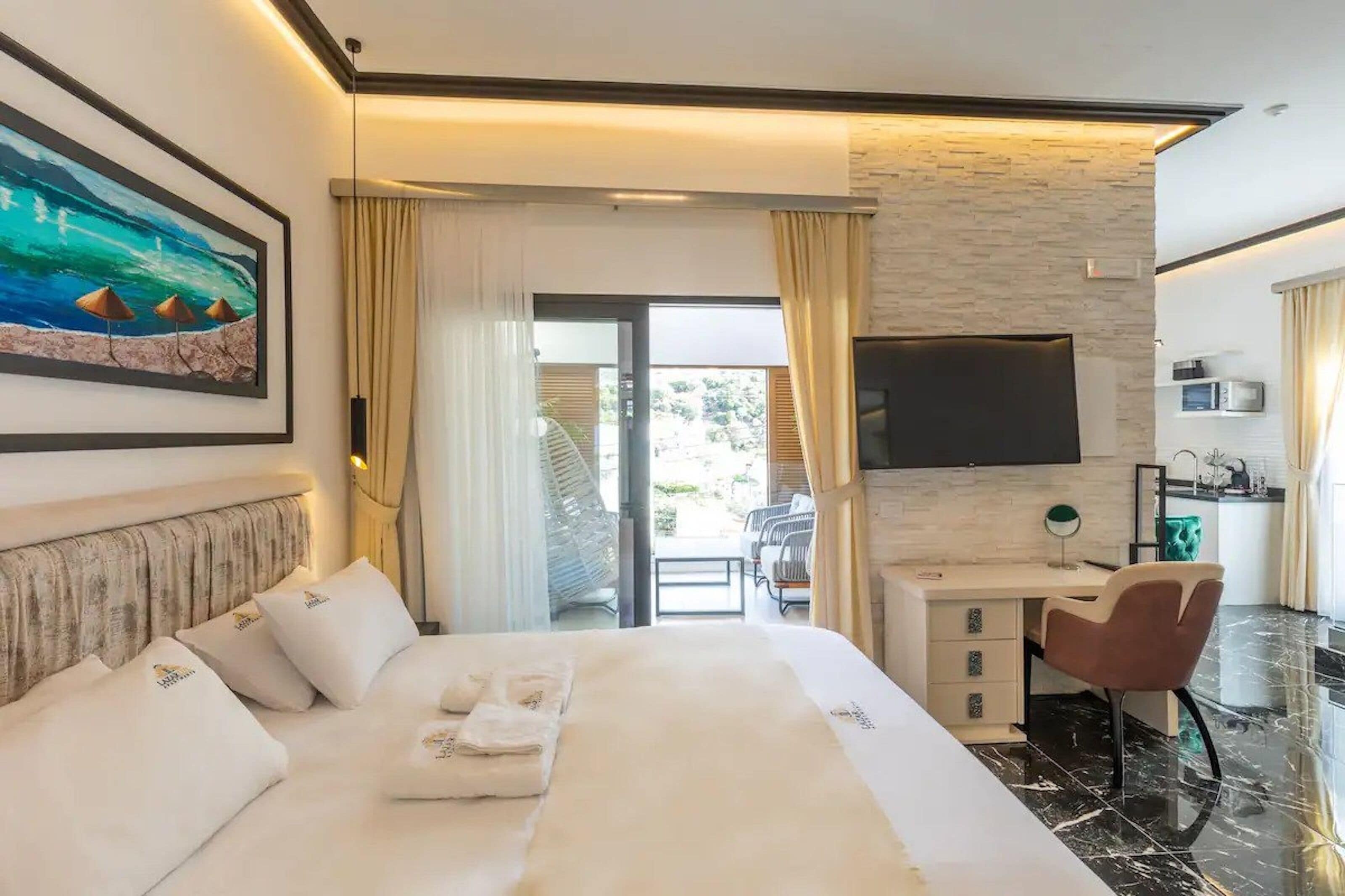 Een hotelkamer met een bed, een bureau met stoel, een televisie en uitzicht op de omgeving.