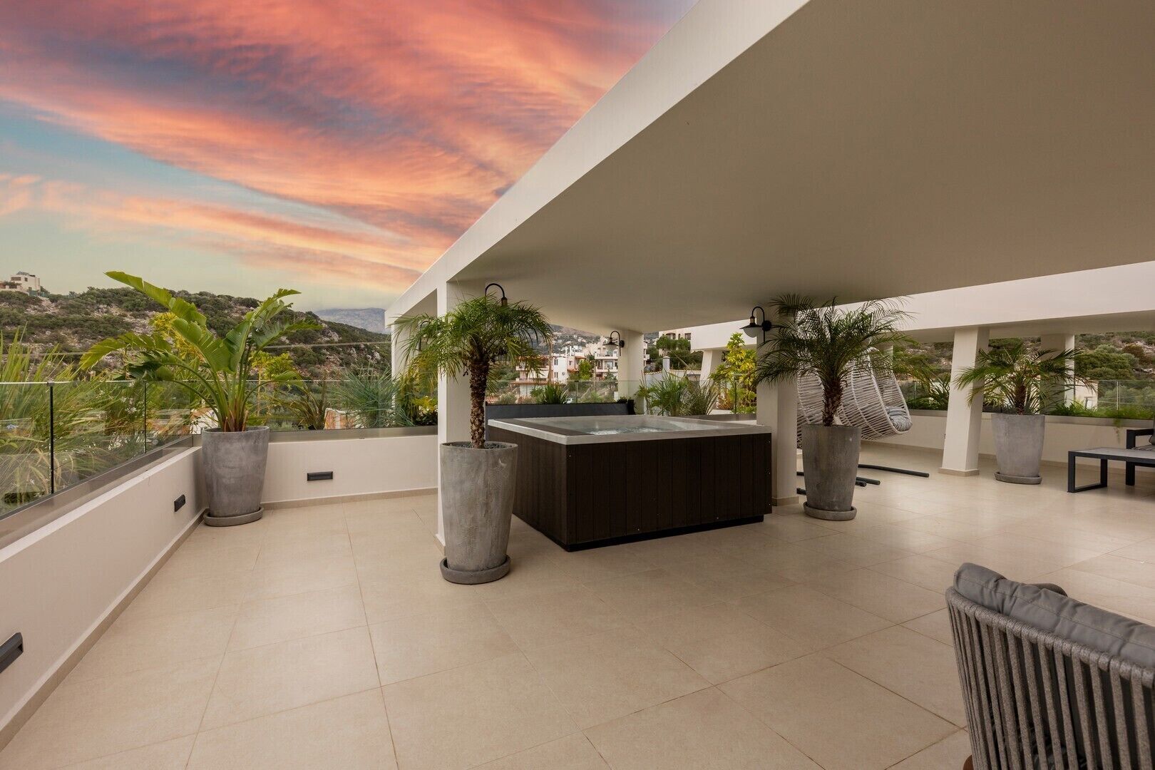 Una terraza en la azotea con cocina exterior moderna, plantas en macetas y vistas del paisaje circundante.