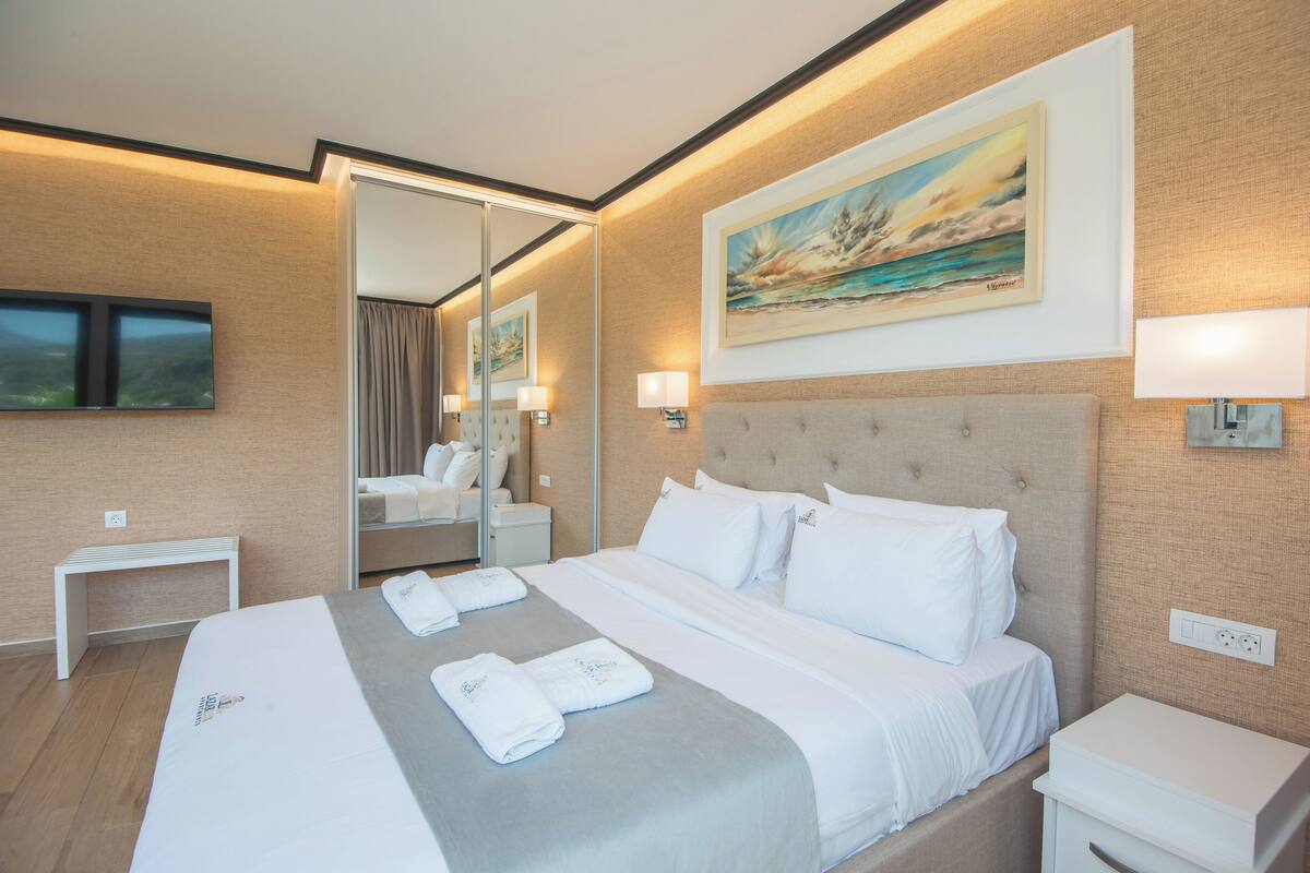 Une chambre d’hôtel avec un grand lit, une table de chevet, un miroir et un tableau au mur.