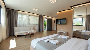 Une chambre d’hôtel moderne avec un grand lit, un canapé, une petite table et un téléviseur.