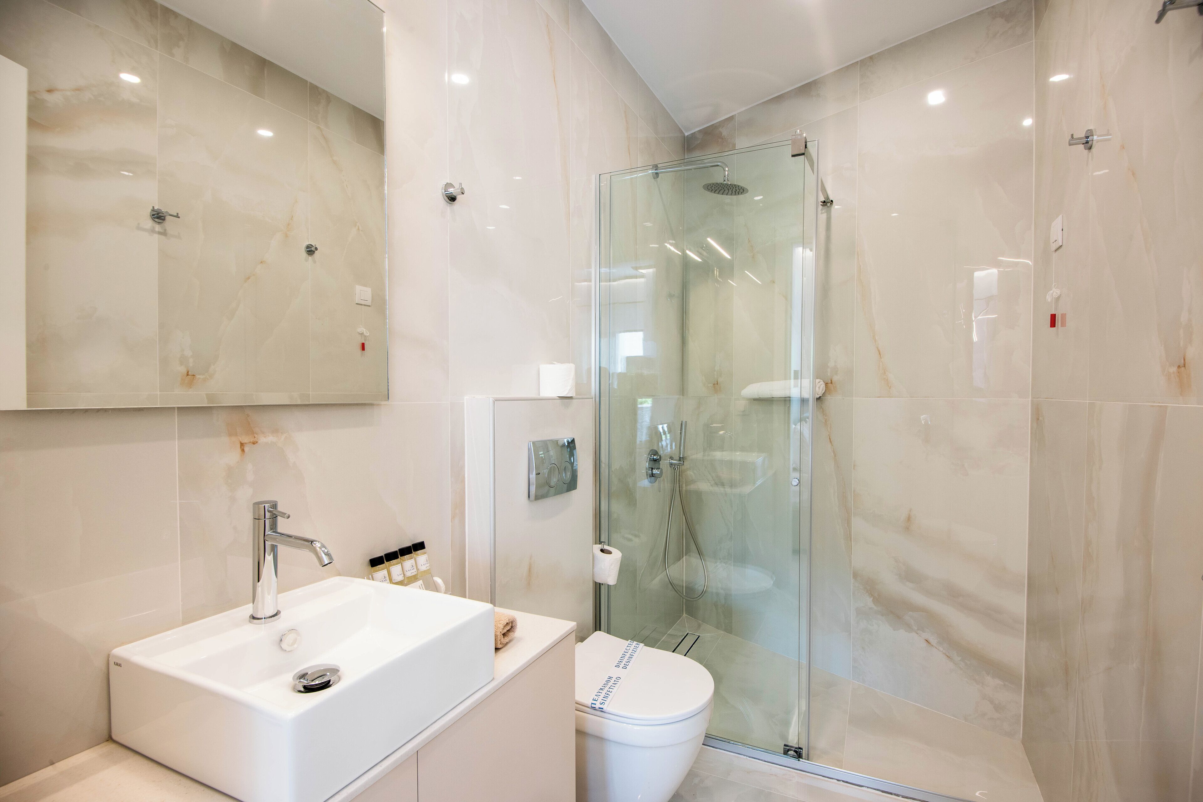 Ein modernes Badezimmer mit einer begehbaren Glasdusche, einem weißen Waschbecken und einer Toilette.