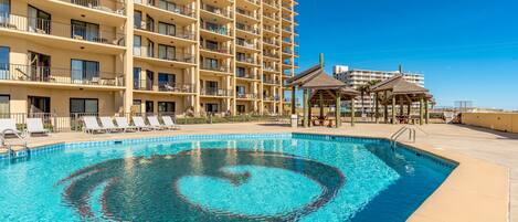 A hotel with a large pool, multiple balconies, and outdoor seating areas.